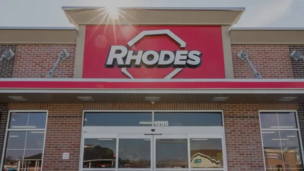 A photo of the exterior of a convenience store. A sign above the doors says Rhodes.