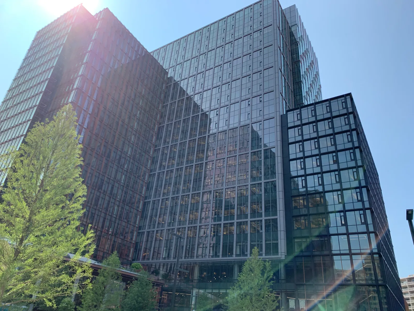 An exterior shot of one of the Met Park buildings, looking up at it. It's a bright day, and the sun reflects off of the glass.