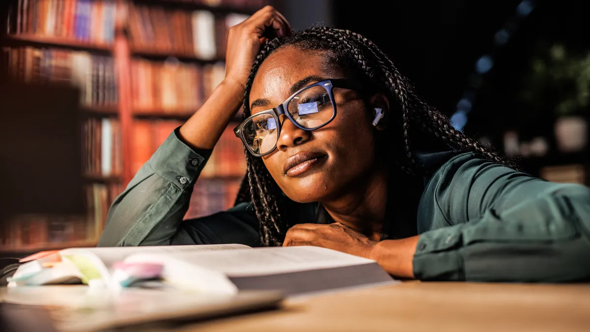 A young college student looks at a textbook in a library.