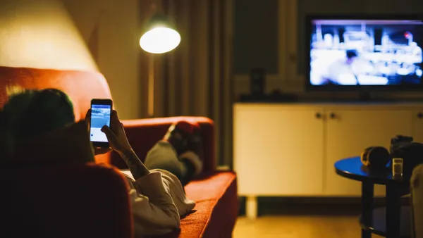 Young woman relaxing with smartphone on sofa