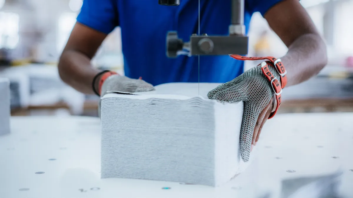 A person's hands are seen running organic cotton through a sewing machine.