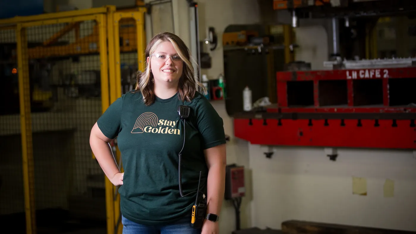 A person wearing a "Stay Golden" t-shirt stands in a GE Appliances facility