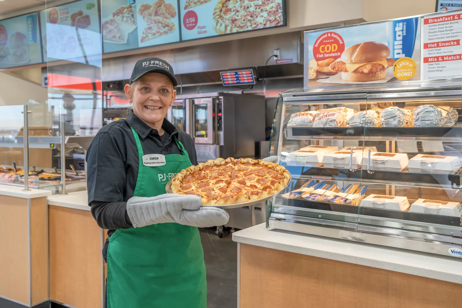 A Pilot employee showcases fresh pizza at one of the company's updated stores.