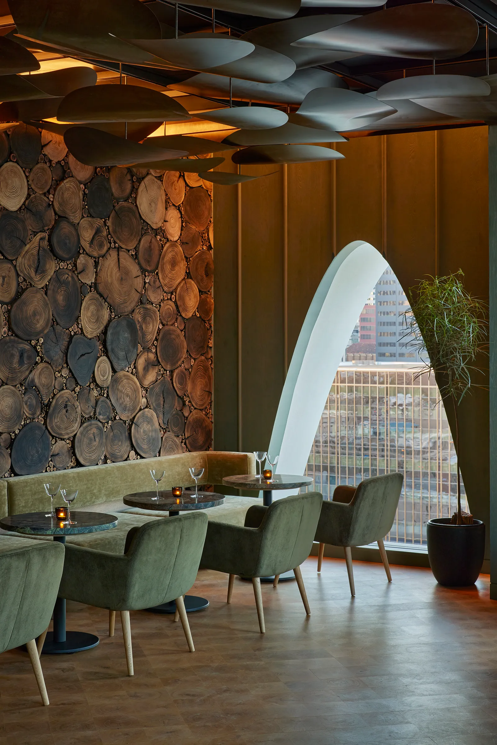 The interior of a restaurant features an oval-shaped window and green chairs.