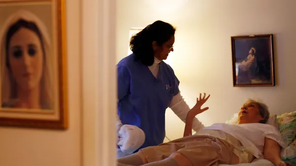 A home health aide assists a patient.
