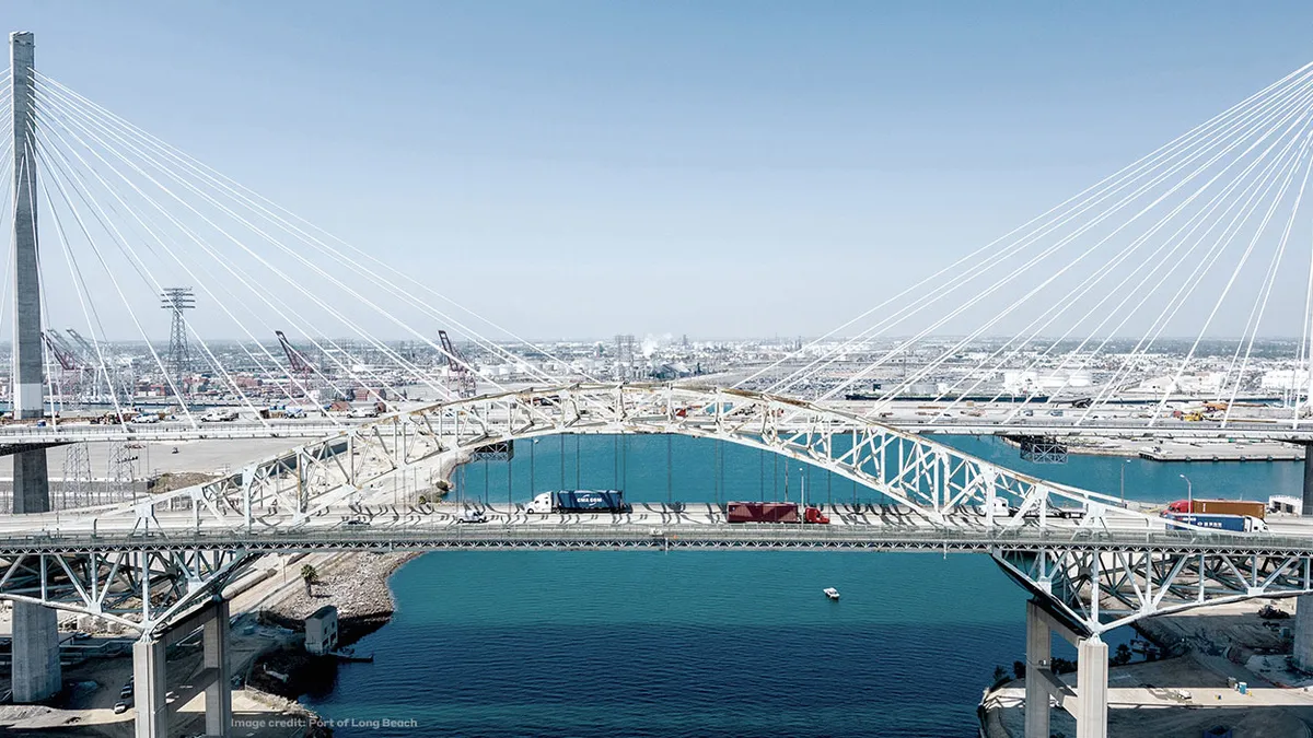 A silver cable-stayed bridge spans bright blue water.