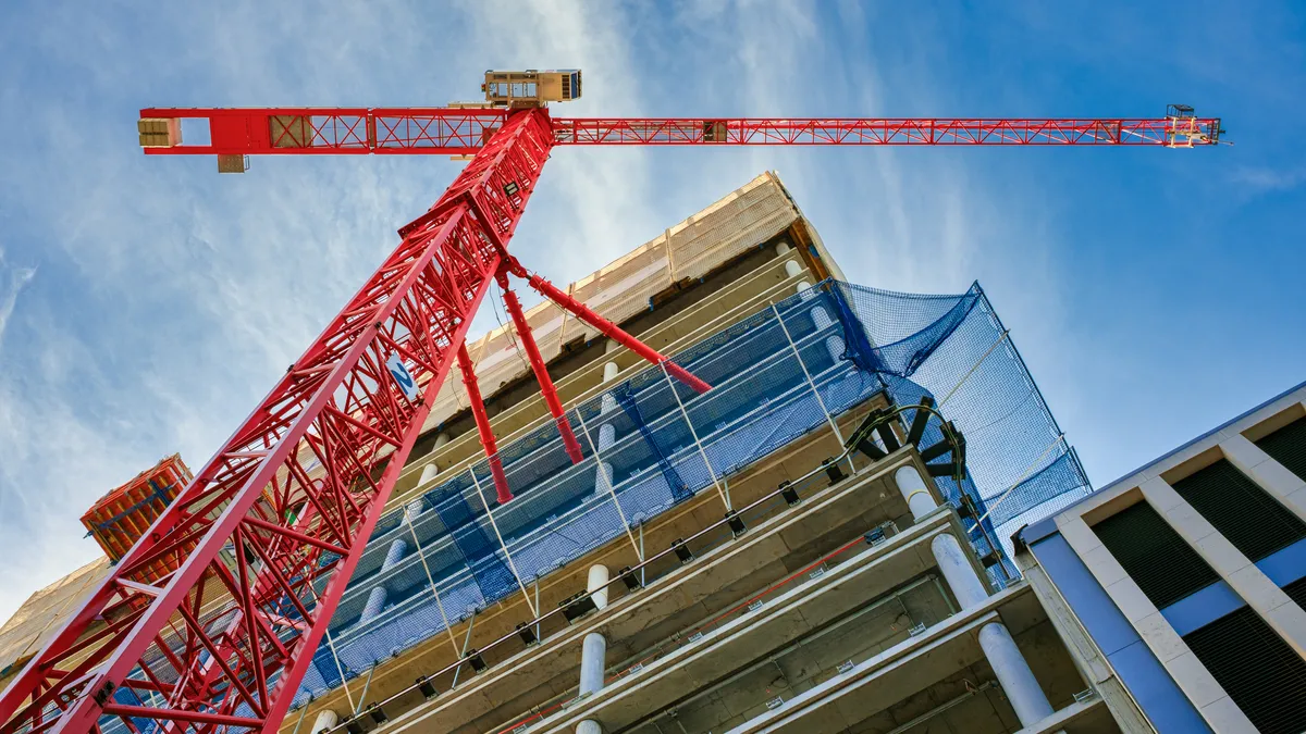 A red construction frame in front of a high-rise building under construction.