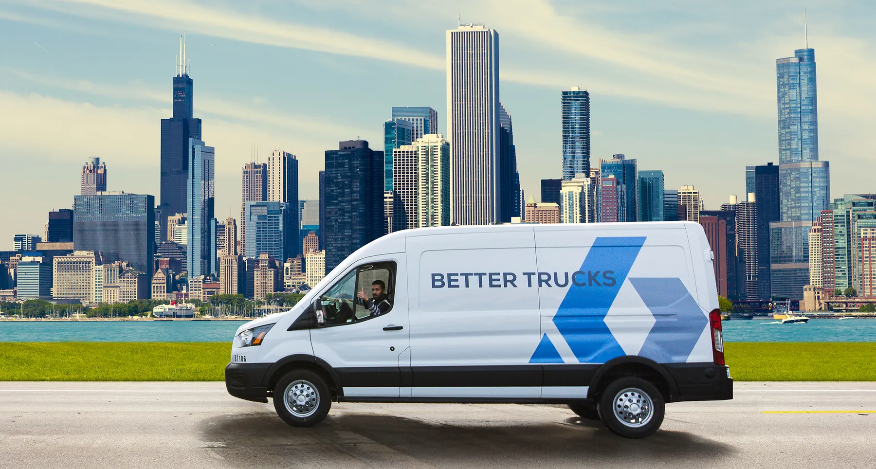 A driver gives a thumbs up in a Better Trucks delivery van.