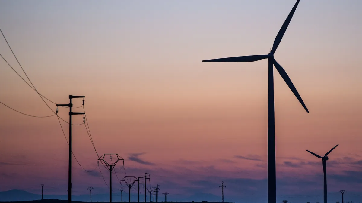 Wind turbines spin next to electricity transmission pylons at a wind farm on February 19, 2015 near Zaragoza, Spain.