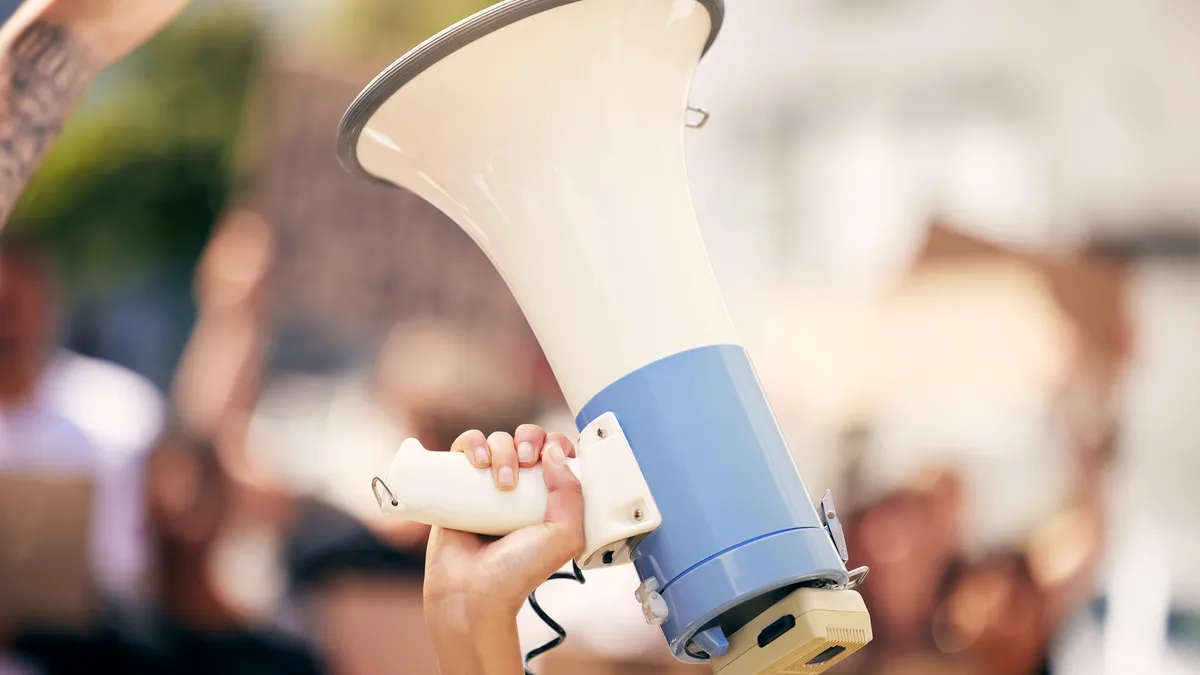 A person sticks a megaphone in the air.