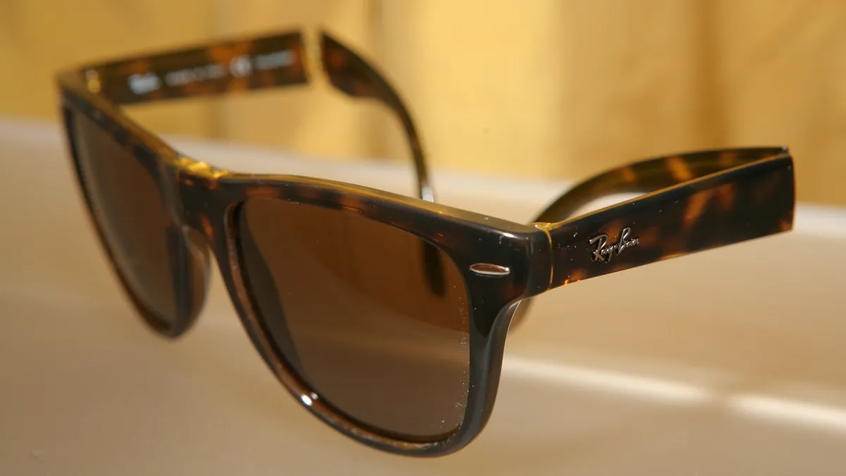 A pair of tortoise-shell Ray-Ban sunglasses sits on a lighted platform.