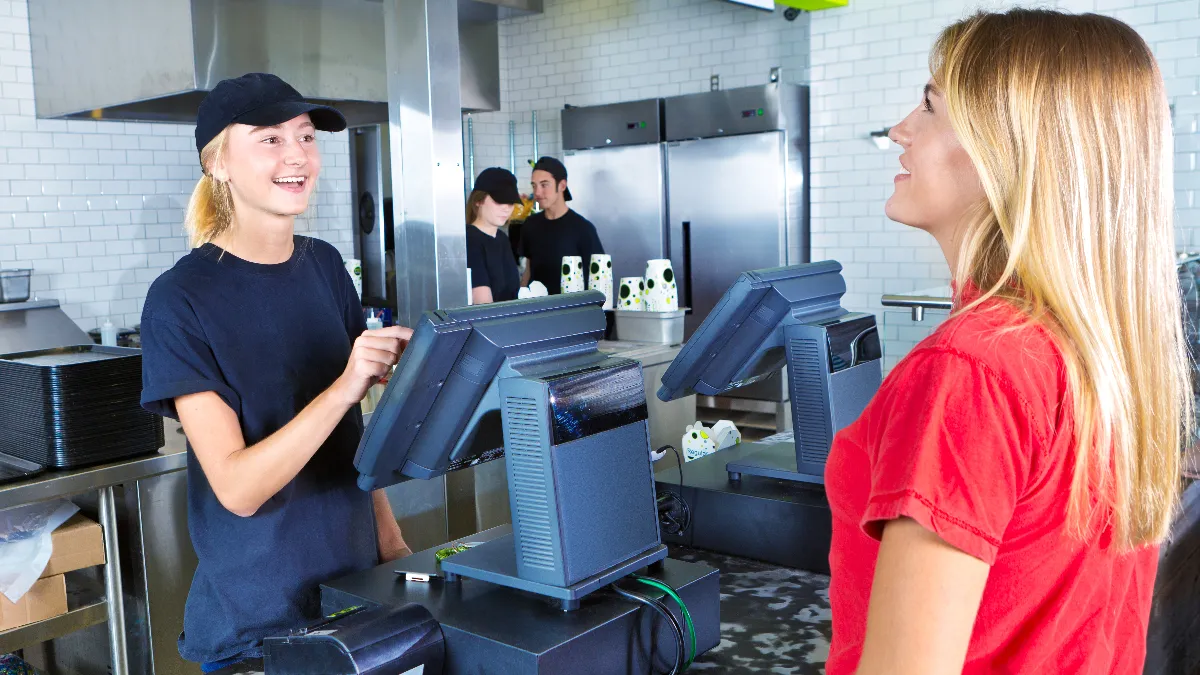 A young woman customer placing her order at a fast food convenience restaurant.