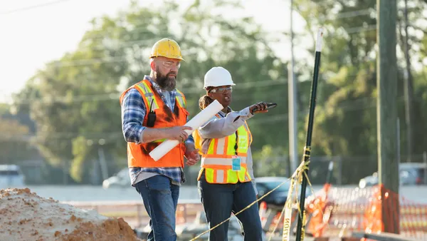Two construction workers collaborate on a jobsite.