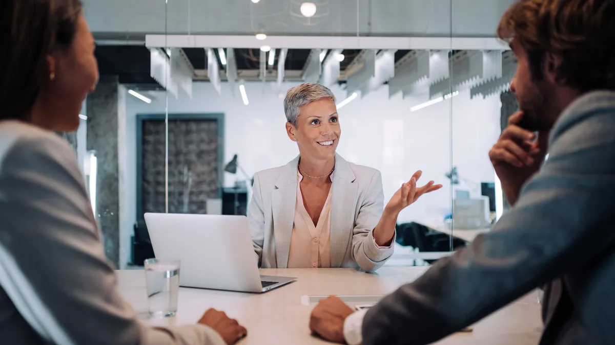 A general counsel sits across a table from her legal operations team in an office