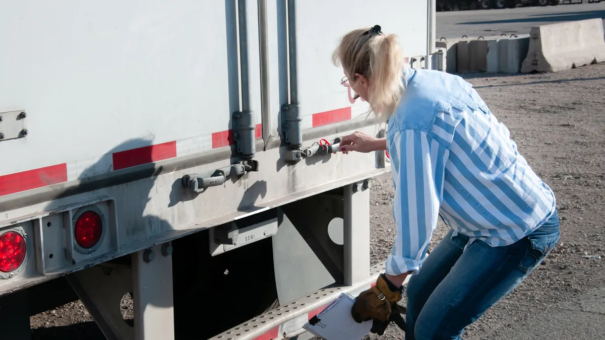 A driver checks a trailer seal number to make sure it matches the numbers on her bill of lading.