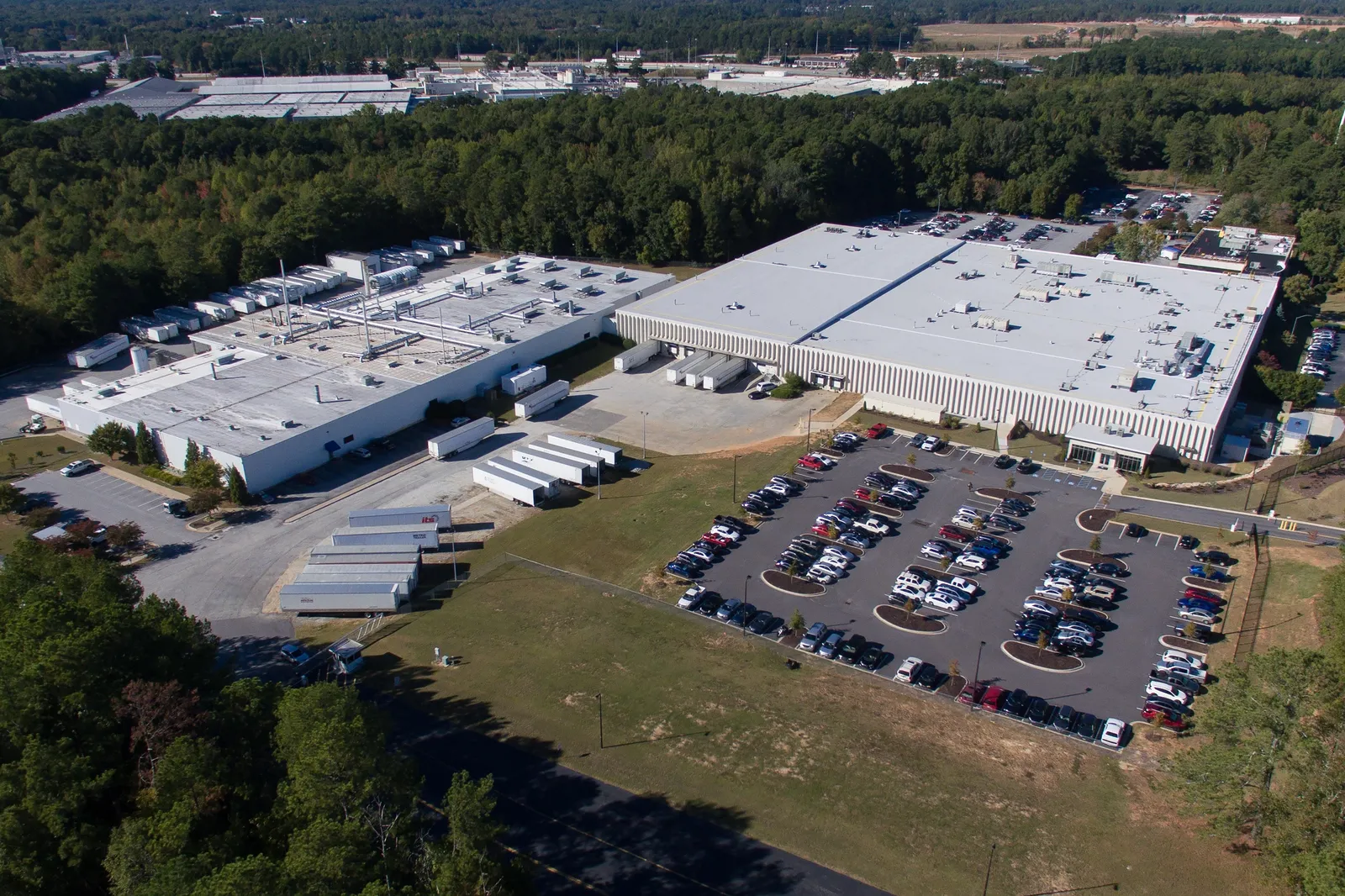 An aerial view of two buildings and a parking lot full of cars.