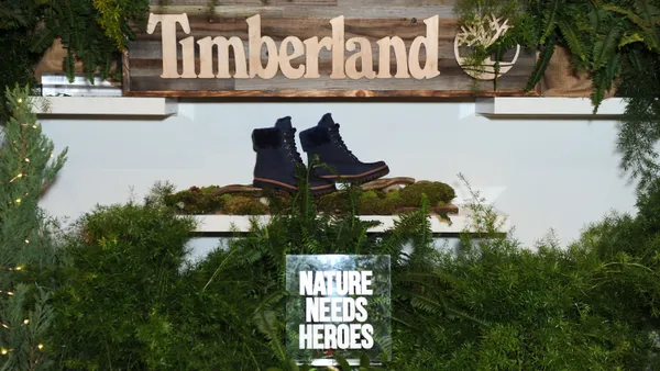 A pair of black Timberland boots is displayed on a stand above a sign that reads "nature needs heroes."