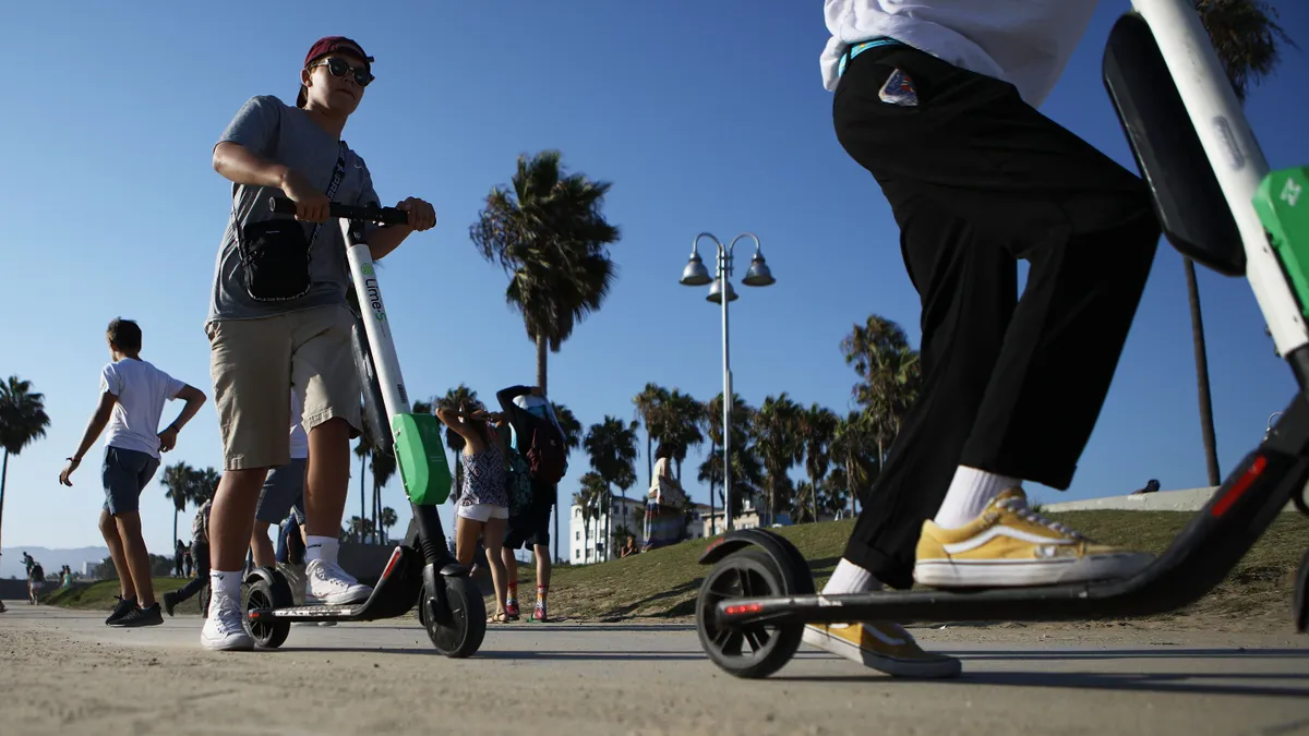 People ride Lime shared dockless electric scooters along Venice Beach on August 13, 2018 in Los Angeles, California.