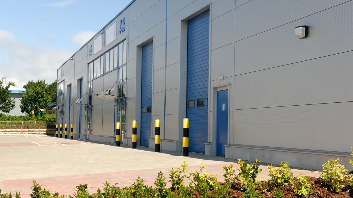 The exterior of a large, modern industrial warehouse unit with blue doors.