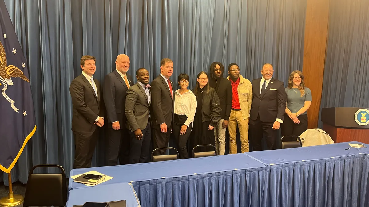 A group of people in business attire pose for a photograph in front of a blue curtain.