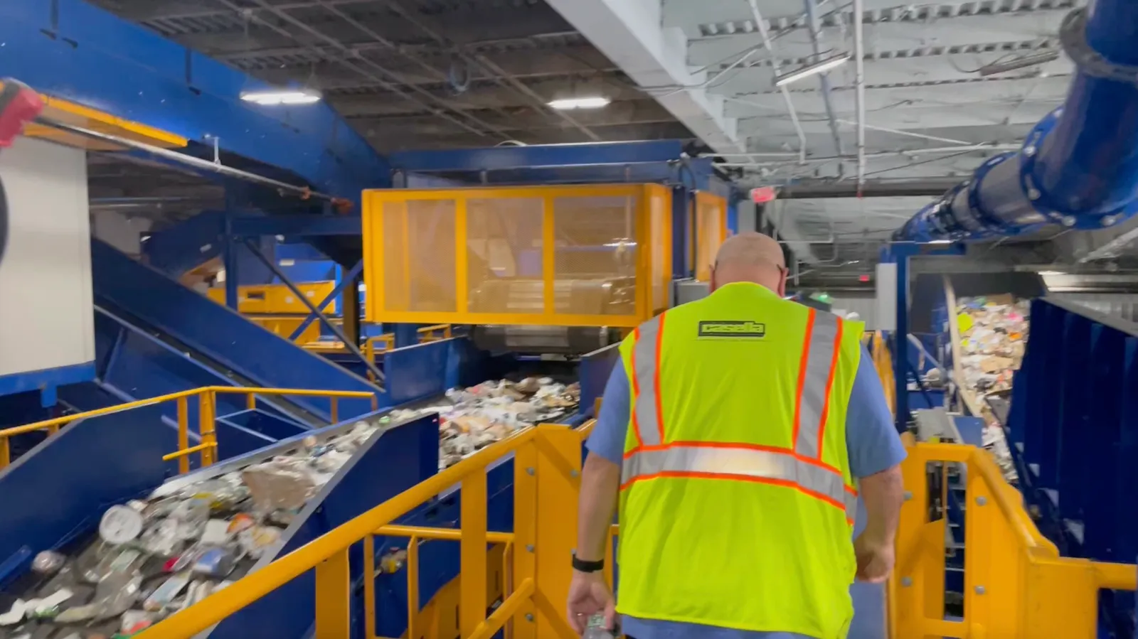 Person in yellow vest walking through industrial facility