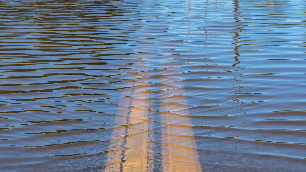 Close-up of double yellow lines on a street covered with floodwater.