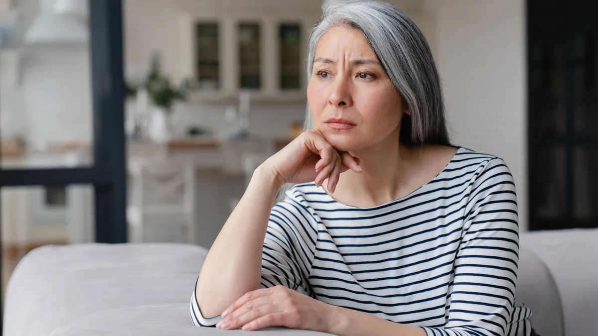 Older Asian woman looks sadly out of the window