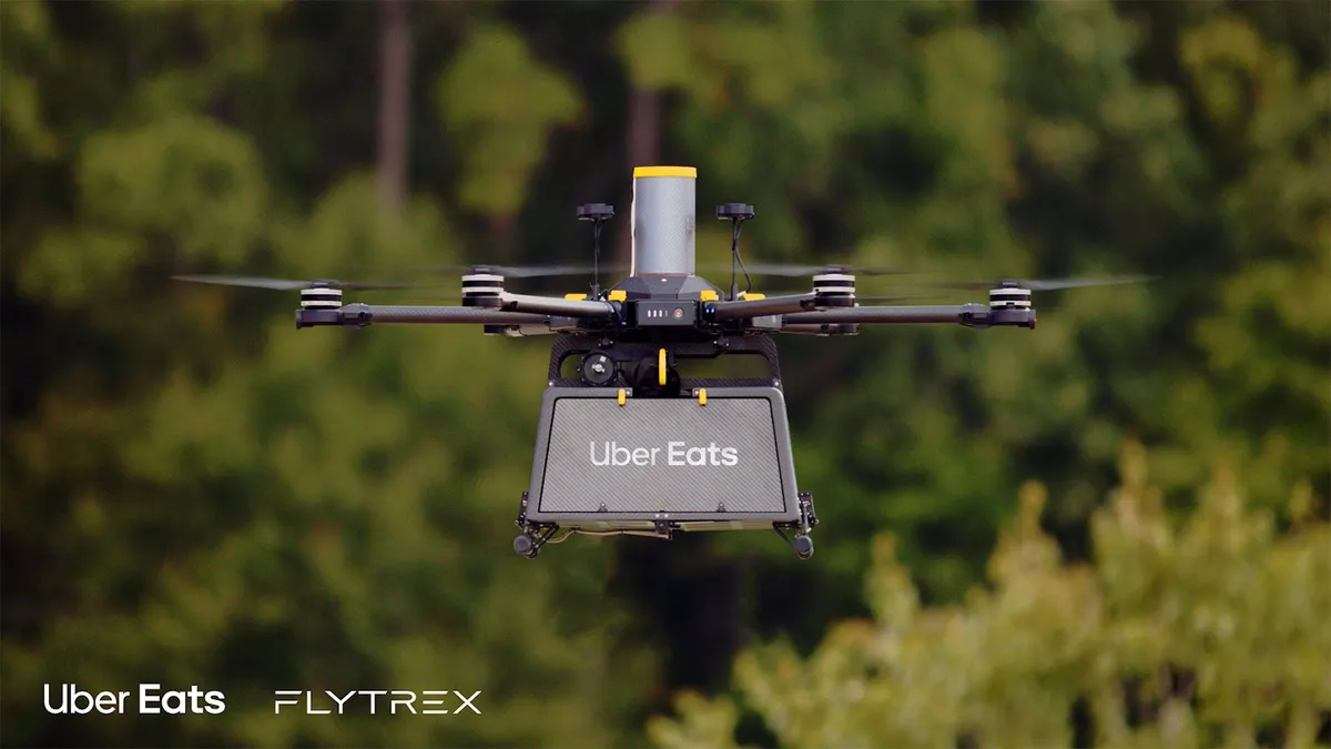 An image of a black drone floating in the air with a green background.