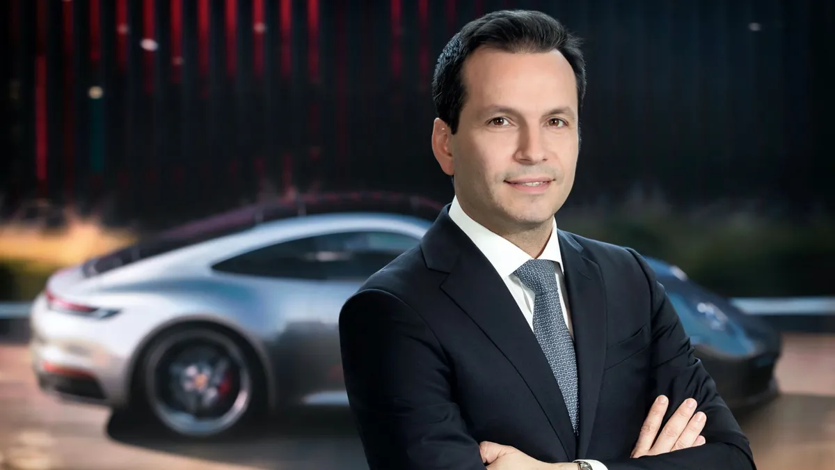 Pictured is John Cappella wearing a dark colored suit with a Porsche vehicle in the background. He was named Executive Vice President and Chief Operating Officer of Porsche North America.