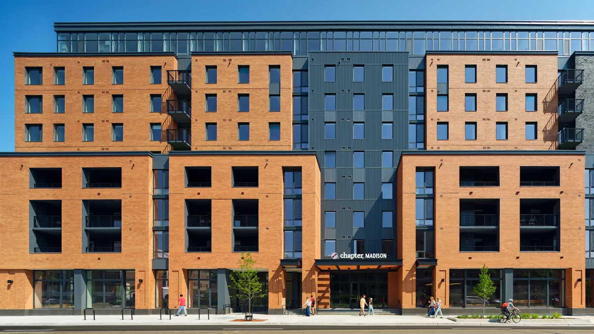 A mid-rise apartment building with a red brick and glass exterior.