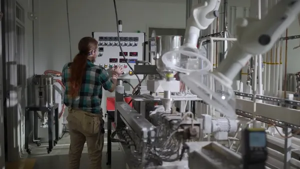 Rear view of a person in a checkered shirt working at a packaging testing facility