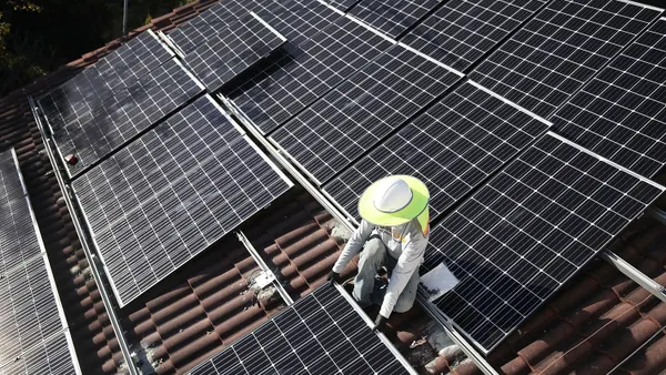 A man installs solar panels on a roof.