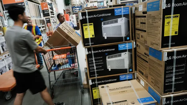 Two men look at a stack of air conditioners in boxes.