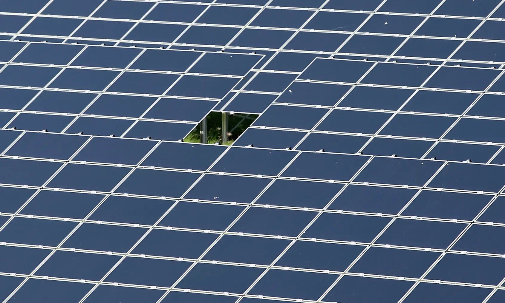 An array of photovoltaic solar panels with one missing from the center.