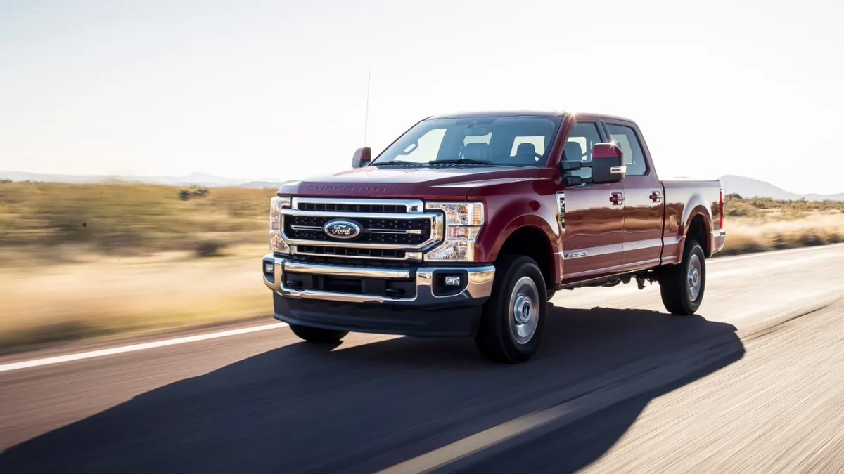 A red 2020 Ford F-250 Lariat Ultimate driving on a road.