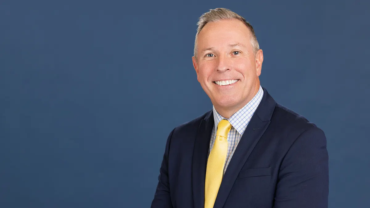 A person in a suit smiles at the camera