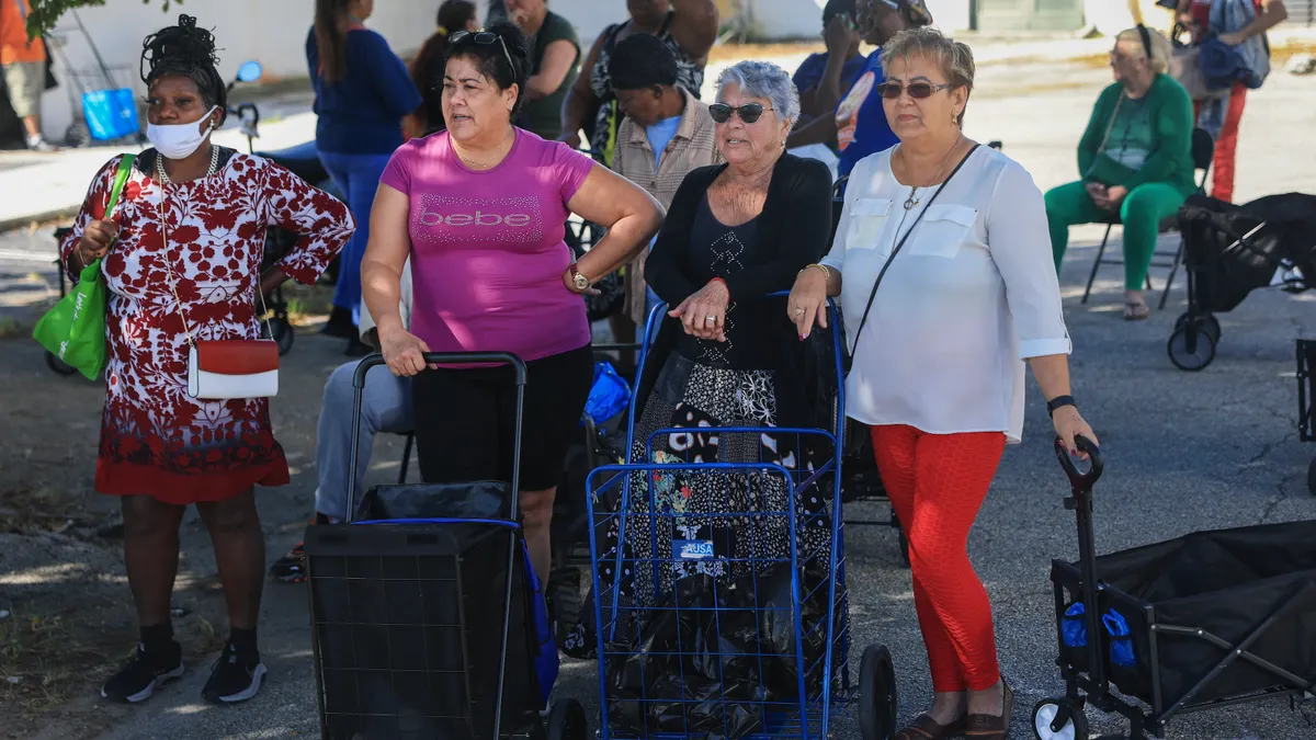 Women wait in line to receive groceries