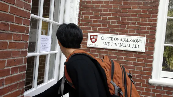 A student enters the admissions office at Harvard University, with a visible sign.