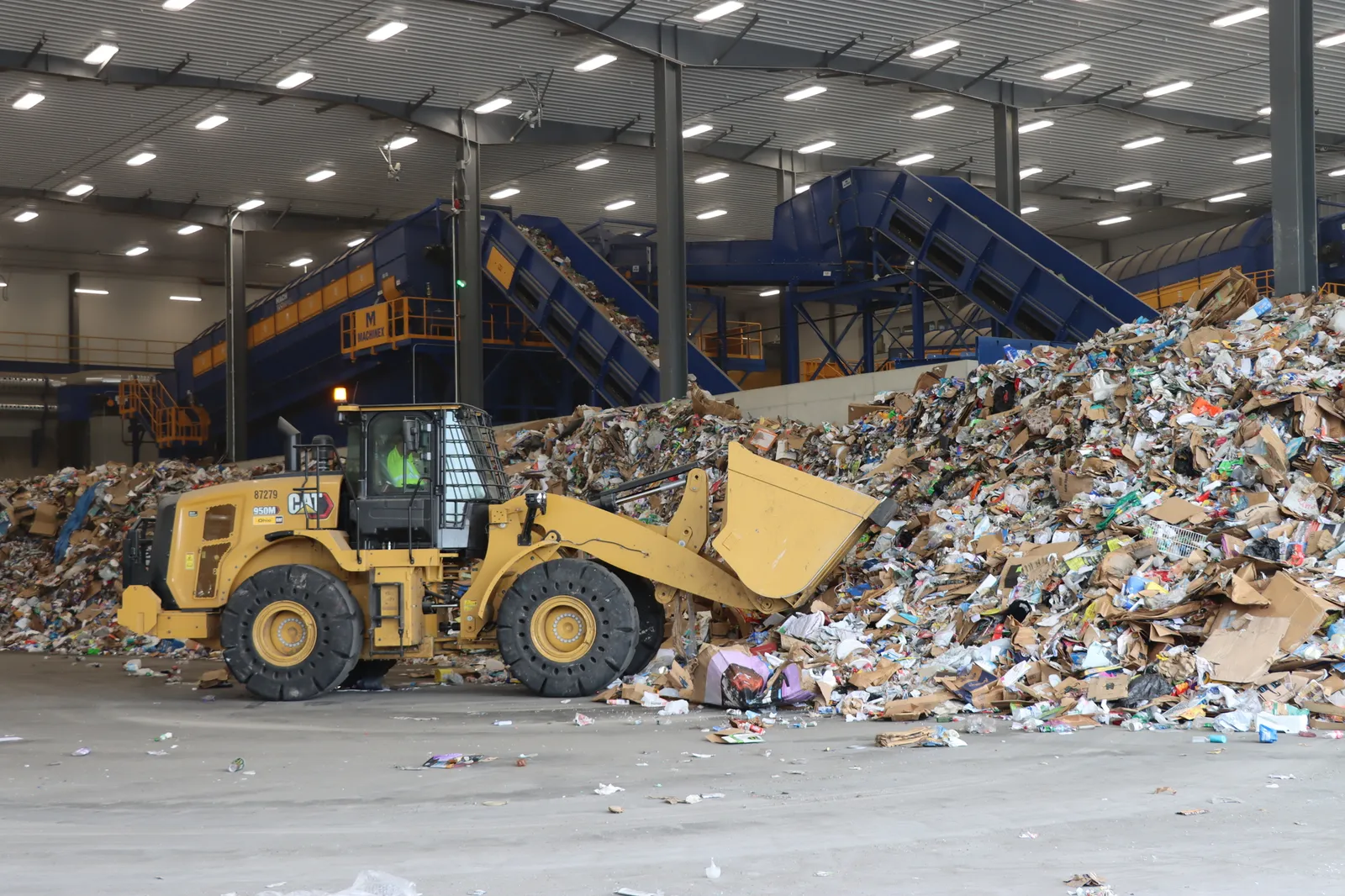 A front loader collects recycled materials in a recycling facility.