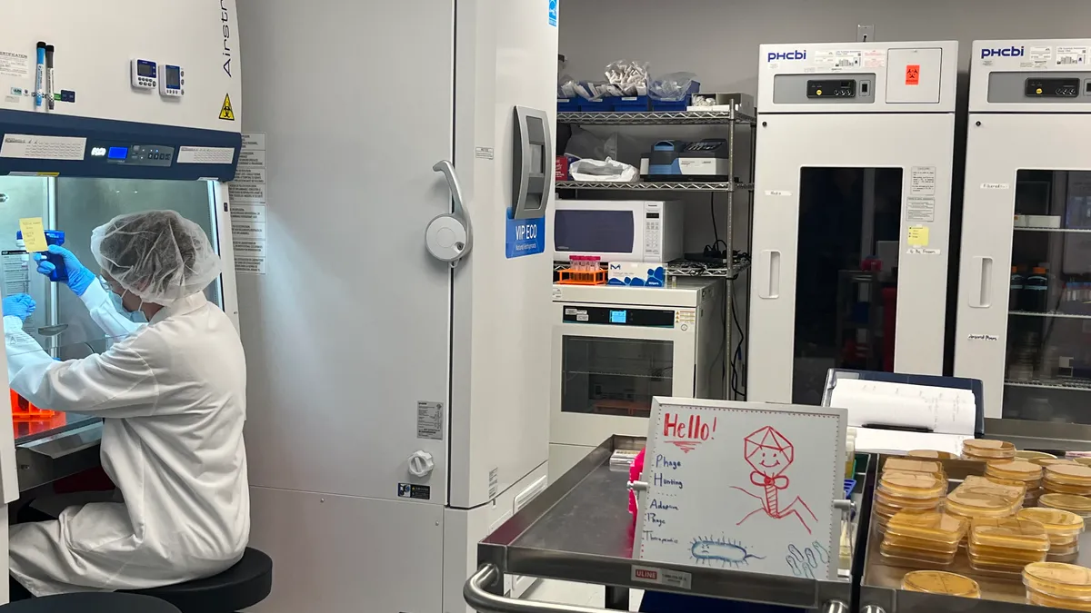 A whiteboard with a stick-figure smiling phage sits on a desk in biotech laboratory