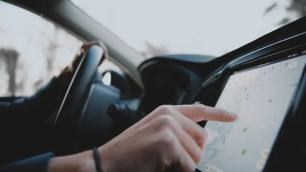 A driver in a vehicle touches an electronic dashboard featuring GPS.