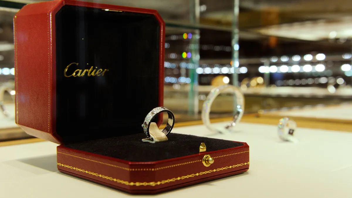 A ring in a red Cartier jewelry box sits on a counter.