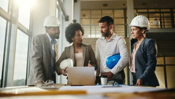 Team of architects talking while working on laptop at construction site.