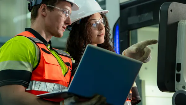 A man and woman discussing wearing construction hats