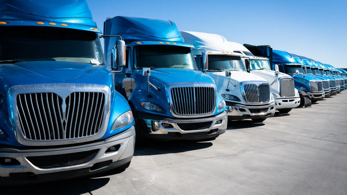 A fleet of blue and white trucks in a lot.