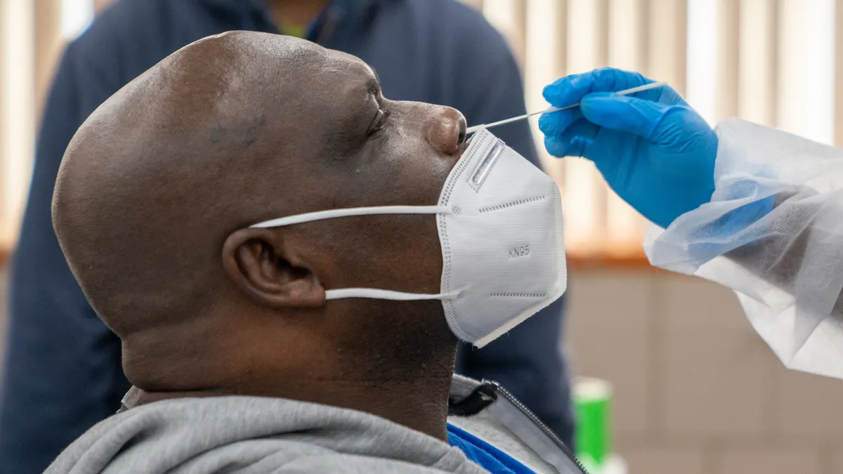 A healthcare professional gives a person a coronavirus test.