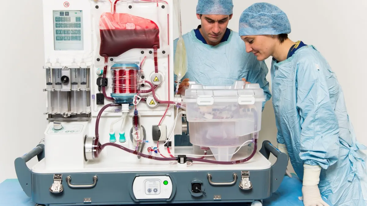 Surgeons wearing scrubs monitor the OrganOx Metra organ preservation system.