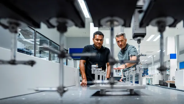 Two people observe equipment in an advanced manufacturing laboratory.