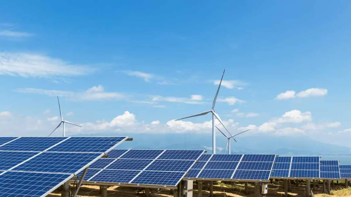 Solar panels and wind farm on a field with blue skies.