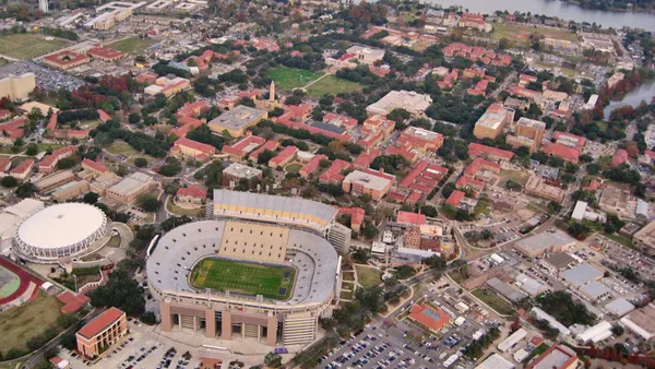 Aerial view of campus including football stadium and red-roofed buildings.